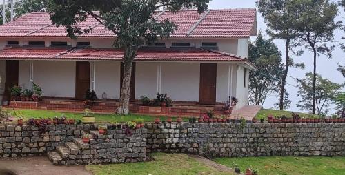 a house with a stone wall in front of it at Moksha at Infinity Valley in Kotagiri