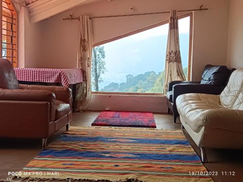 a living room with a couch and a large window at Moksha at Infinity Valley in Kotagiri