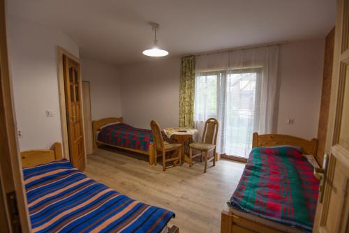 a room with two beds and a table and a window at Willa Pod Jasieniami -basen plac zabaw in Białka Tatrzanska