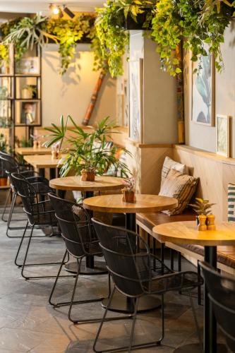 a row of tables in a restaurant with plants at Hotel Indigo Antwerp City Centre by IHG in Antwerp