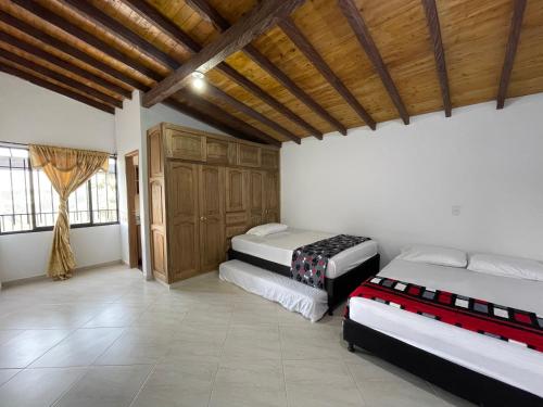 a bedroom with two beds and a wooden ceiling at Mirador la piedra in Guatapé