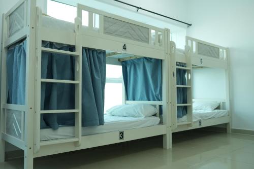 Cette chambre comprend 2 lits superposés avec des rideaux bleus. dans l'établissement Hawana Premium Hostel, à Dubaï