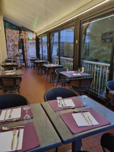 un comedor con mesas, sillas y ventanas en Logis hôtel restaurant les Carillons, en Cransac