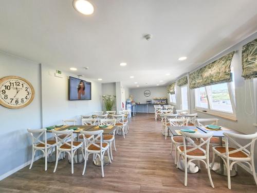 ein Restaurant mit Tischen und Stühlen und einer Uhr an der Wand in der Unterkunft Sea & Sun Hospedaria Recomeçar in Torres Vedras