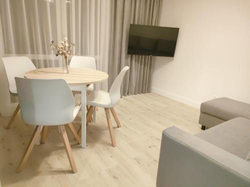 斯克拉斯卡波伦巴White Apartament Szklarska Poręba的餐桌、白色椅子和电视