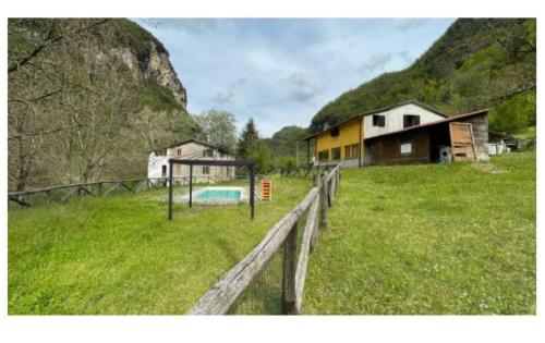 una casa en un campo con una valla y un parque infantil en Luxury suite la Grotta del Vento, en Gallicano