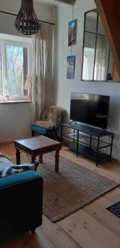 ein Wohnzimmer mit einem Flachbild-TV und einem Tisch in der Unterkunft Appartement 1er étage duplex in Briançon