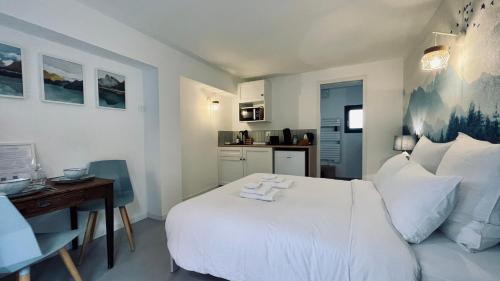 a bedroom with a white bed and a desk and a kitchen at Le Chalet de la Plage in Sévrier