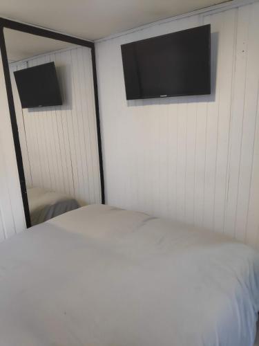 een slaapkamer met een bed en een flatscreen-tv bij Habitación privada tipo hotel, Baño, TV y WiFi. in Bogota