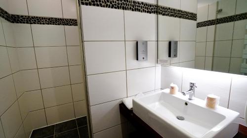 a white bathroom with a sink and a mirror at Boutique Logis Hôtel Relais de Vincey in Vincey
