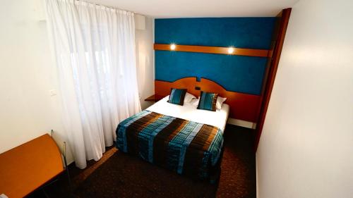 a hotel room with a bed and a blue wall at Boutique Logis Hôtel Relais de Vincey in Vincey