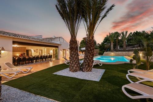 a backyard with two palm trees and a swimming pool at Villa Joan - PlusHolidays in Calpe