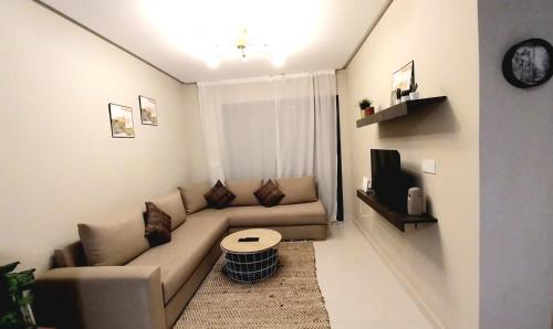 a living room with a couch and a tv at Cosy appartement proche de l'aéroport mohamed 5 in Deroua