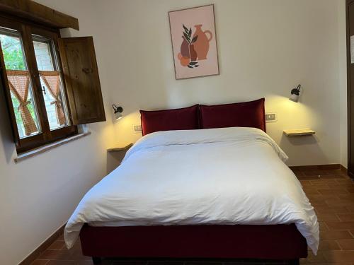 a bedroom with a bed with white sheets and red pillows at Agriturismo Il Mulino delle canutole in Magione