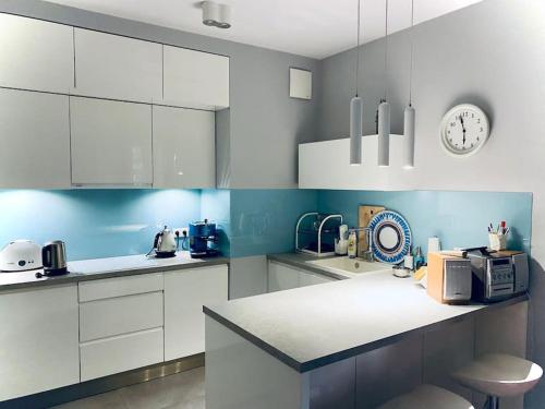 a kitchen with white cabinets and a clock on the wall at KOMFORTOWY,JASNY APARTAMENT dla max 4-5 osób in Łódź