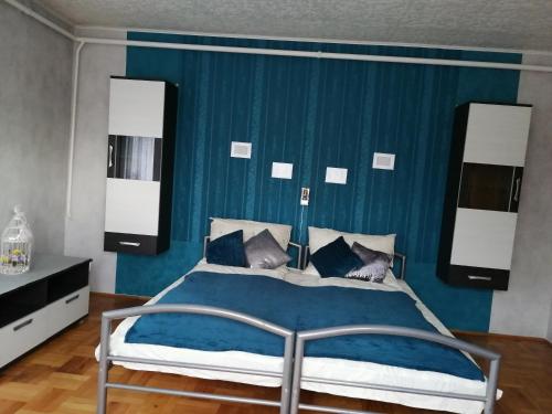 1 dormitorio con 1 cama con pared azul en Fitt Vendégház, en Sümeg