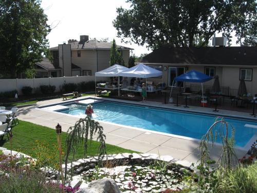 una piscina con mesas y sombrillas en un patio en Hidden Retreat, Hot Tub, Relax! Upstairs of home., en Sandy