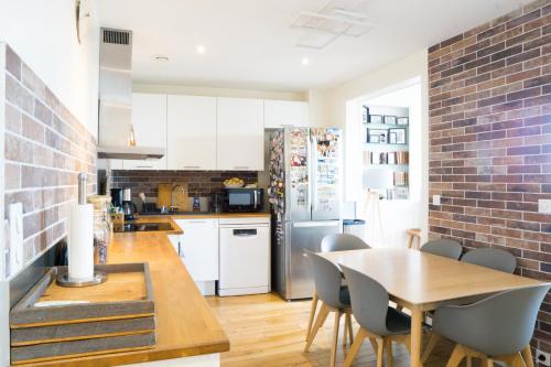 eine Küche mit einem Esstisch und einer Ziegelwand in der Unterkunft EXIGEHOME-Appartement cosy avec vue sur la tour Eiffel in Saint-Cloud