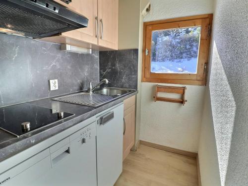 une petite cuisine avec un évier et une fenêtre dans l'établissement Duplex Chaleureux, Skis aux Pieds - Proche Commerces, 6 Pers., Balcon Sud - FR-1-182-231, à Les Allues