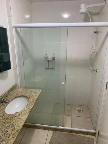 um chuveiro com uma porta de vidro ao lado de um lavatório em Belezas da Prainha em Arraial do Cabo
