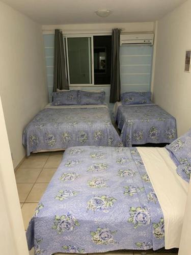 um quarto com 3 camas com edredões azuis em Belezas da Prainha em Arraial do Cabo