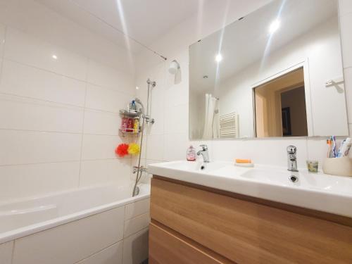 ein Badezimmer mit einem Waschbecken, einer Badewanne und einem Spiegel in der Unterkunft EXIGEHOME-Appartement cosy avec vue sur la tour Eiffel in Saint-Cloud