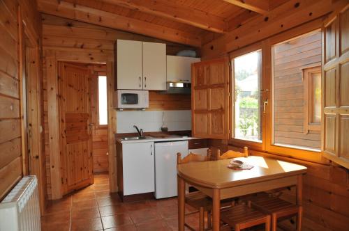 cocina con mesa y horno de fogón blanco en Bungalows Sol e Mar, en Hío