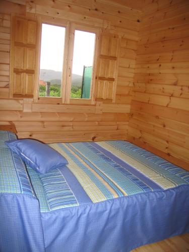 a bedroom with a bed in a log cabin at Bungalows Sol e Mar in Hio