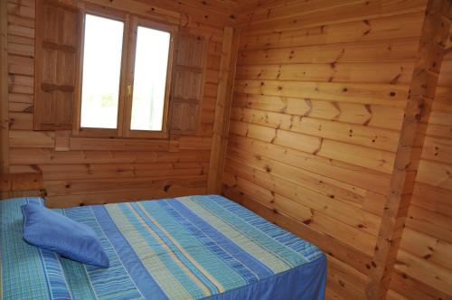 a bedroom in a log cabin with a bed at Bungalows Sol e Mar in Hio