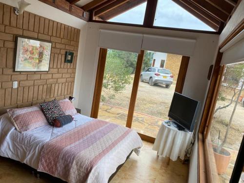 een slaapkamer met een bed, een tv en een raam bij Casa campestre Las Flores in Villa de Leyva