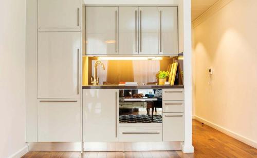 a kitchen with white cabinets and a table at Monument Serviced Apartments in London
