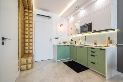 a kitchen with green and white cabinets and a sink at Q18 ApartHotel in Bydgoszcz