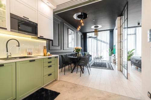 a kitchen with green cabinets and a dining room at Q18 ApartHotel in Bydgoszcz