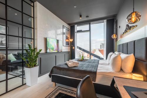 a bedroom with a bed and a desk and a large window at Q18 ApartHotel in Bydgoszcz