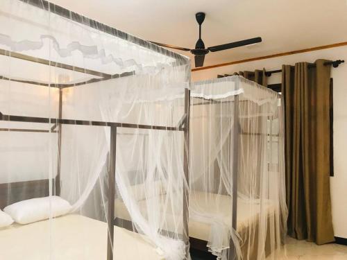 a bedroom with a bed with white curtains at Samaro Resort in Matara