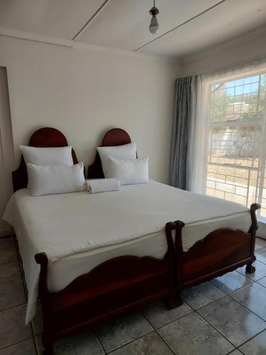 1 cama grande en un dormitorio con ventana en New Lodge, en Bloemfontein