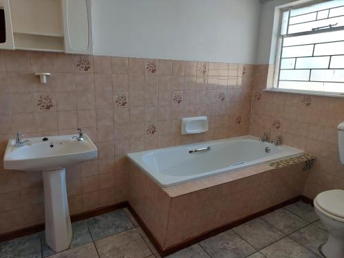a bathroom with a tub and a sink and a toilet at New Lodge in Bloemfontein