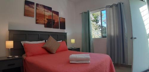 a bedroom with a red bed and a window at Corte de Los Angeles in Puerto Morelos