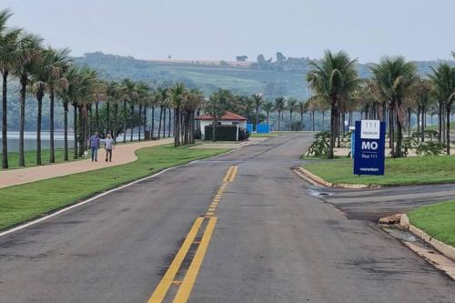 an empty road with palm trees and a no parking sign at Riviera de Santa Cristina III, piscina e represa, tijolinho vermelho in Itaí