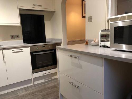 a kitchen with white cabinets and a microwave at The Grooms Den in Fenny Compton