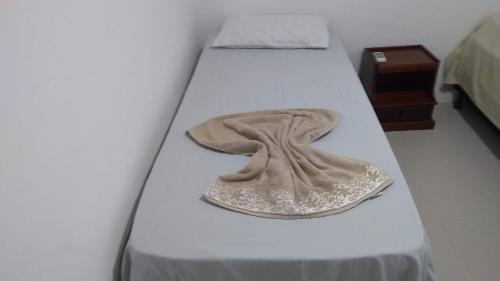 uma cama com um cobertor e uma toalha em Apartamento frente para a piscina a uma quadra da praia em Florianópolis