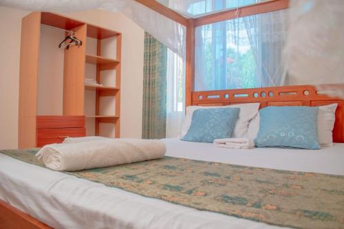 a bedroom with a bed with blue pillows and a window at Unique Homes One- Bedroom Apartment in Kilifi