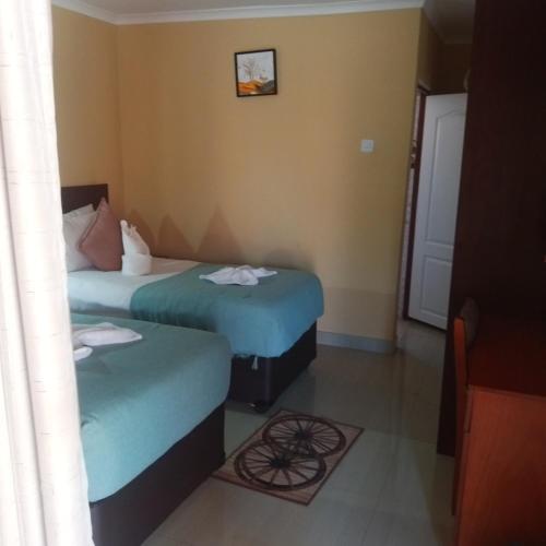 a hotel room with two beds and a door at Impovu Guest House in Kasane