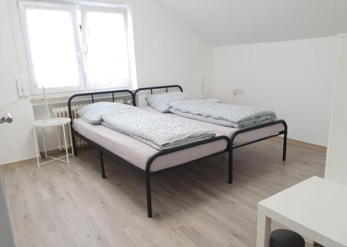 Habitación blanca con 2 camas y suelo de madera. en Kaiser, en Friedrichshafen