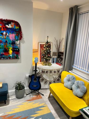 a living room with a yellow couch and a guitar at Stay-K-Belfast Cosy house 10 mins from city centre in Belfast