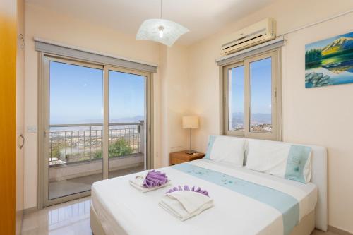 a bedroom with a bed and two large windows at Villa Panorama Tessera in Droushia