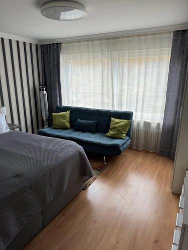 a bedroom with a blue couch in front of a window at Apartments an der Caracalla Therme in Baden-Baden
