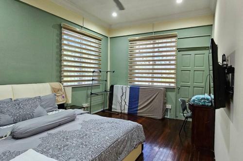 a bedroom with green walls and a bed and two windows at Kenyalang Piasau Homestay in Miri