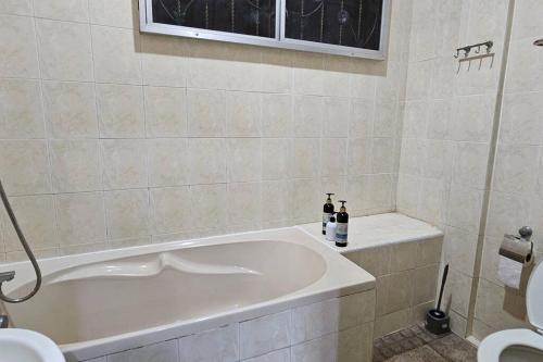 uma casa de banho com banheira e 2 garrafas de vinho em Kenyalang Piasau Homestay em Miri