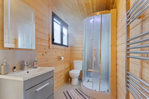 a bathroom with a toilet and a sink and a shower at Nestledstays- The Farm Lodge in Slindon